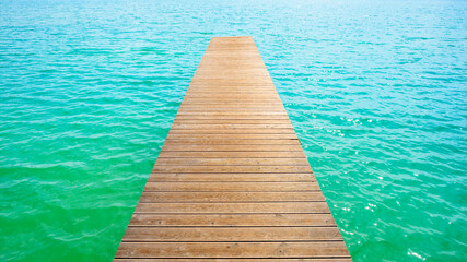 Summer background, wooden footbridge on swimming lake with turquoise water