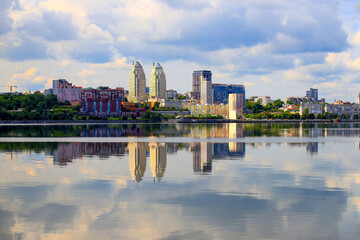 Obraz premium Summer river view of a big city. Clouds over the Dnieper, skyscrapers and towers are reflected in the water. Dnipro city, Dnepropetrovsk, Ukraine, cityscape.