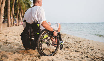 Disabled man in a wheelchair on the beach.