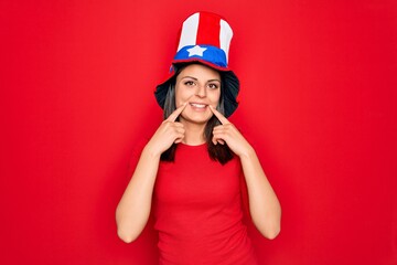 Young beautiful brunette woman wearing united states hat celebrating independence day Smiling with open mouth, fingers pointing and forcing cheerful smile