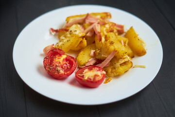 Baked potatoes with bacon, cheese and tomatoes in a plate.