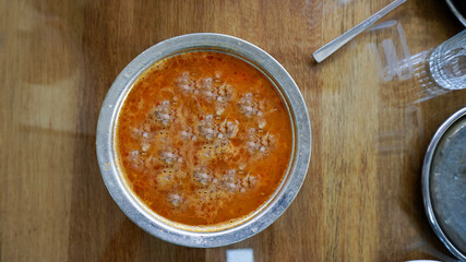 Beyran soup in a bowl / plate with spoons on the wooden table. Traditional hot soup of Gaziantep, Turkey. Closeup of a famous Turkish cuisine fresh food foams. Meat ingredients in regional breakfast.