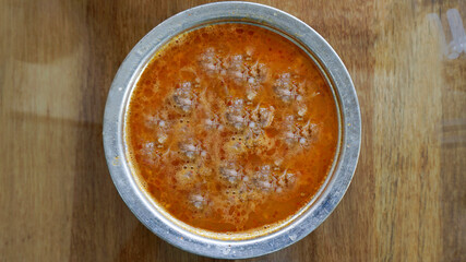 Beyran soup in a bowl / plate with spoons on the wooden table. Traditional hot soup of Gaziantep, Turkey. Closeup of a famous Turkish cuisine fresh food foams. Meat ingredients in regional breakfast.