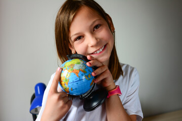 Portrait of a beautiful young schoolgirl girl exploring the globe through a magnifier. day of knowledge. beginning of the school year. studying geography with globe