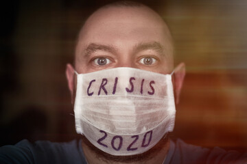 The coronavirus crisis. A man in a medical mask with the inscription - Crisis 2020.