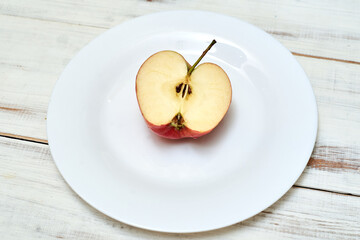 Half an apple on a plate on a wooden background.