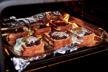Making sandwiches from toast bread with minced meat, egg and cheese in the oven.