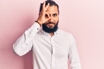 Fototapeta premium Young arab man wearing casual clothes doing ok gesture with hand smiling, eye looking through fingers with happy face.
