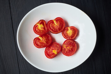 Grilled baked tomatoes in the oven on a white plate.