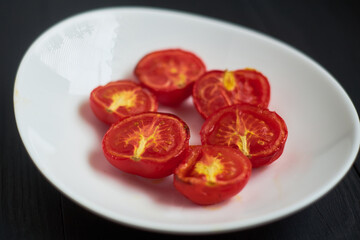 Grilled baked tomatoes in the oven on a white plate.