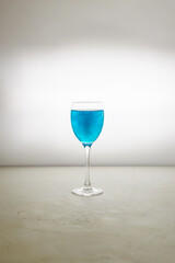Glass of blue glitter drink on a light background. Sparkling blue wine.