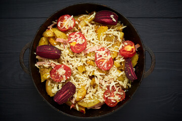 Baked potato with meat, tomatoes, beetroot in the oven. Sprinkled with cheese.