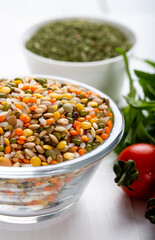 Colorful various beans or lentils and whole grains seeds or cereal in bowl with fresh vegetables on wooden background.