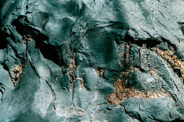 A black-green piece of bitumen with a tar in the form of a stone with wood filings. Abstract natural background with unique texture.