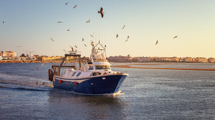 Fishing boat at sunset arriving at the port of Isla Cristina, after a long day at work in the waters of the Atlantic Ocean, Spain © jarcosa