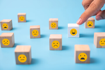 man hand pick up smile face from bad face group of wood cube.Human resources and team management...