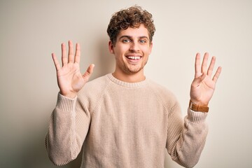 Young blond handsome man with curly hair wearing casual sweater over white background showing and...