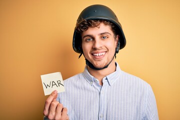 Young blond businessman with curly hair wearing helmet holding paper with war message with a happy face standing and smiling with a confident smile showing teeth