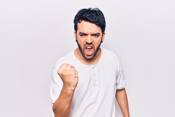 Young hispanic man wearing casual clothes angry and mad raising fist frustrated and furious while shouting with anger. rage and aggressive concept.