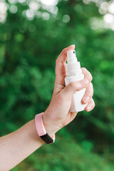 Woman using antiseptic spray outdoors