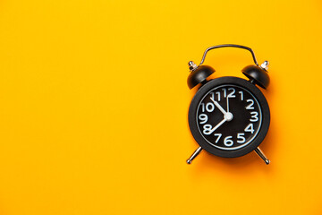 Black alarm clock on orange bright timetable