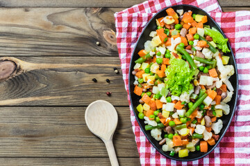 Lemon sesame  vegetables saute  in cast iron skillet. Top view, wooden background.