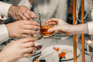 hands hold glasses with whiskey. festive atmosphere