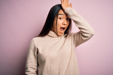 Young beautiful asian woman wearing casual turtleneck sweater over pink background surprised with...