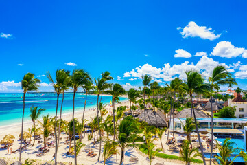 Aerial drone view of beautiful atlantic tropical beach with palms, straw umbrellas and boats. Bavaro, Punta Cana, Dominican Republic. Vacation background.