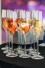 nine glasses of champagne on the table. stack of plates in the background