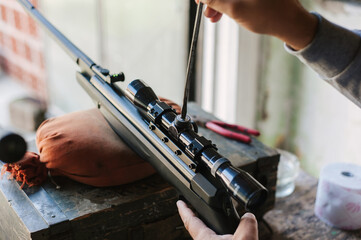 The gunsmith adjusts the optical sight of the sport air rifle. Adjusting the sniper rifle at a...