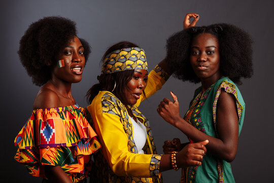 Three young beautiful African fashion models have fun and laughing in traditional dress. Women from the Congo Republic, Ivory Coast, and Zimbabwe