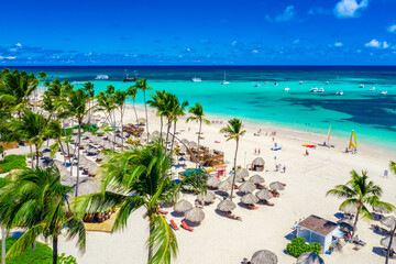 Aerial drone view of beautiful atlantic tropical beach with palms, straw umbrellas and boats....