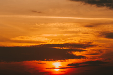 Fototapeta na wymiar Magical orange bright sunset with sunbeams and dark gloomy clouds. Twilight background, nightly dramatic wallpaper. Meteorology, weather forecast. Warm golden sky. Sun disk