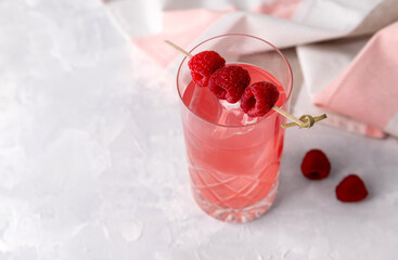 Pink rose iced cocktail with raspberry in crystal glass on table