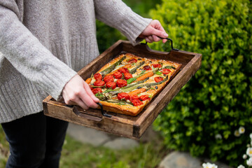 woman holds a tray of focaccia in the courtyard
