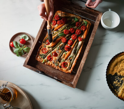 a woman prepares focaccia with whole carrots and asparagus
