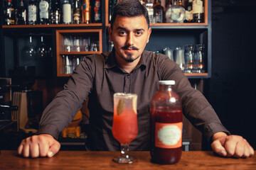 Portrait of elegant, young bartender with moustache behind the bar