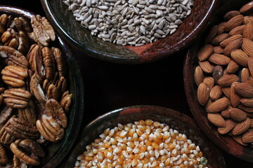 Four different bowls with almond, pecans, pumpkin seeds, popcorn kernels