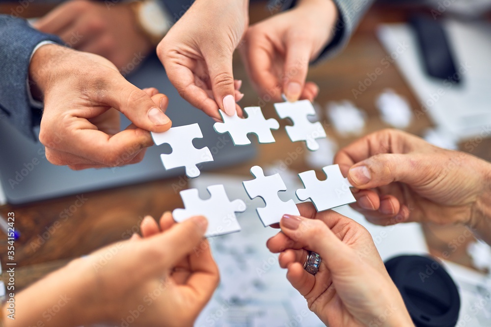 Wall mural group of business workers with hands together connecting pieces of puzzle at the office