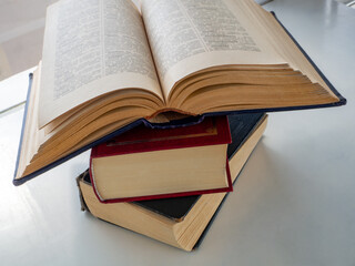 A stack of three old books that lie on top of each other. The top book is open. Background for libraries, science, education.