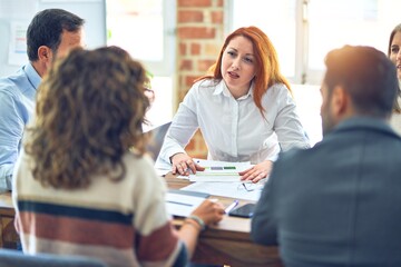 Group of business workers working together. Sitting on desk speaking at the office