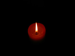 an orange lighted candle in the dark. Candle flame.