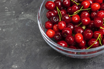 sweet red cherries in a glass bowl on the gray concrete background