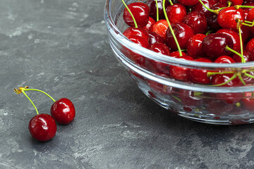 sweet red cherries in a glass bowl on the gray concrete background