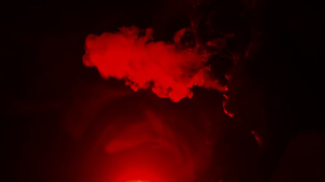 girl smoking vape red smoke on black background