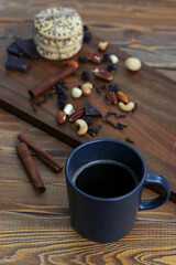 black cup of black coffee close up on the background cakes, nuts and cinnamon on the serving red wooden board