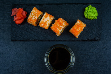 Sushi roll philadelphia with salmon, rice, cheese, cucumber, avocado and caviar on a slate board. Japanese food. Top view