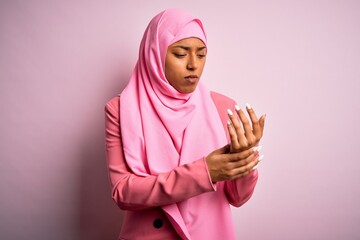 Young African American afro woman wearing muslim hijab over isolated pink background Suffering pain...