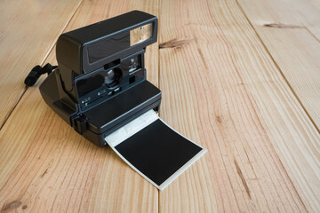 instant camera with a just printed photograph on a wooden background